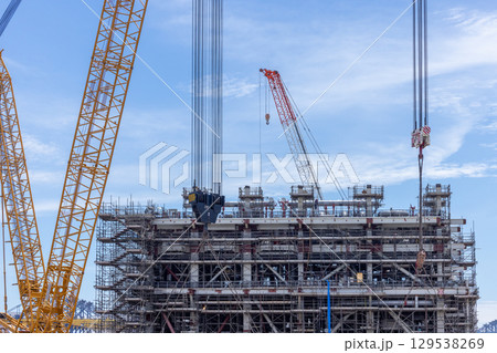 Construction site with construction crawler cranes and multi storey unfinished buildings, Many high rise cranes and industrial construction equipment, Contruction site bl;ue sky background. 129538269