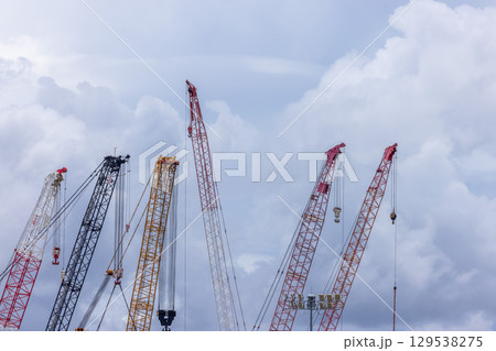 Crawler crane on blue sky white clouds background, Real estate industry. Red crawler crane use reel lift up equipment in construction site. Crane for rent. Crane dealership for construction business. Crawler crane on blue sky white clouds background, Real estate industry. Red crawler crane use reel lift up equipment in construction site. Crane for rent. Crane dealership for construction business. 129538275