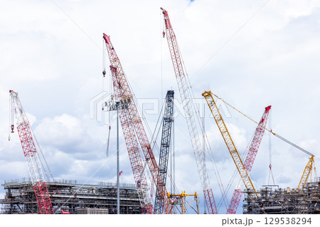 Construction site with construction crawler cranes and multi storey unfinished buildings, Many high rise cranes and industrial construction equipment, Contruction site bl;ue sky background. Construction site with construction crawler cranes and multi storey unfinished buildings, Many high rise cranes and industrial construction equipment, Contruction site bl;ue sky background. 129538294
