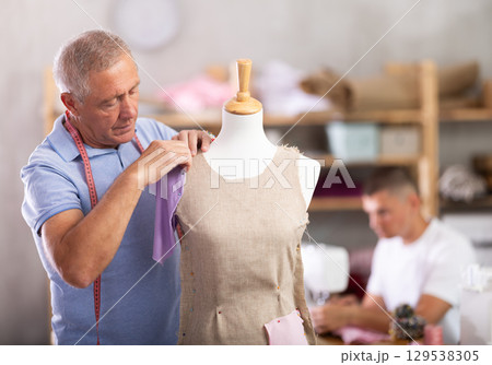 Mature tailor working with mannequin against the background of specialist 129538305