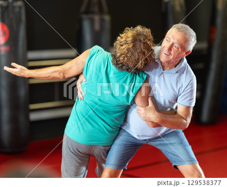 Focused senior man grappling in amateur wrestling session 129538377