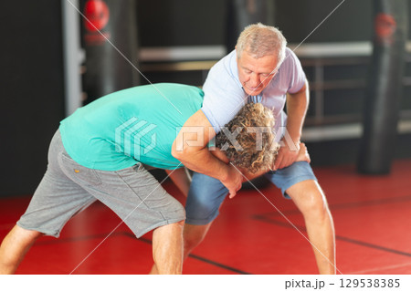 Senior man practicing self-defense techniques in sparring Senior man practicing self-defense techniques in sparring 129538385