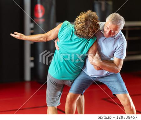 Senior man practicing self-defense techniques in sparring 129538457