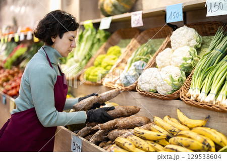 Woman shop seller puts cassava goods on display case 129538604