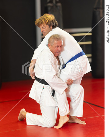 Senior aikido practitioner training with partner in dojo Senior aikido practitioner training with partner in dojo 129538613
