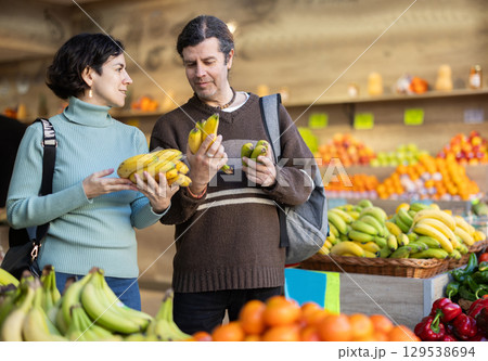 Married couple chooses bananas and other fruits at supermarket counter Married couple chooses bananas and other fruits at supermarket counter 129538694