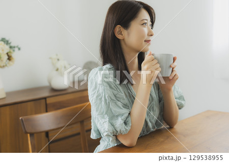 部屋でコーヒーを飲む若い女性 129538955