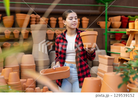 Portrait of woman choosing pots for flowers in gardening market Portrait of woman choosing pots for flowers in gardening market 129539152