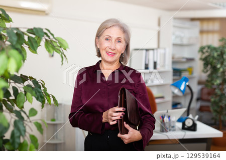Businesswoman standing in office with document case 129539164