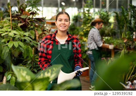 Woman florist withe plastic watering can in floral shop Woman florist withe plastic watering can in floral shop 129539192