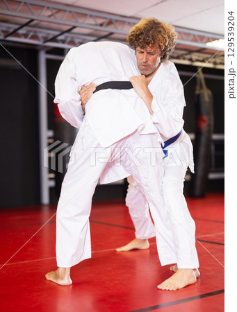 Jiu‑jitsu fighter practicing techniques on red tatami 129539204