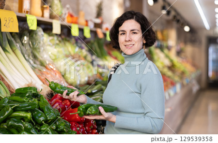 Adult woman chooses peppers in vegetable shop Adult woman chooses peppers in vegetable shop 129539358