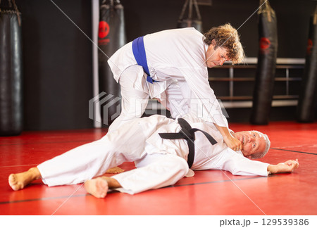 Middle‑aged aikido practitioner training with partner in dojo Middle‑aged aikido practitioner training with partner in dojo 129539386