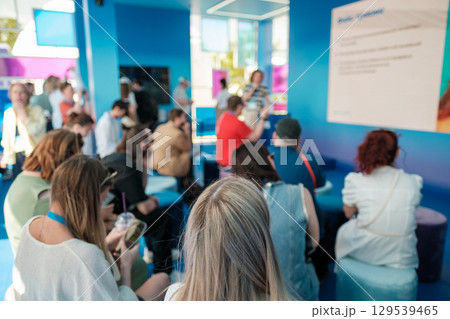 Group listening to a presentation in a modern blue-themed seminar setting 129539465