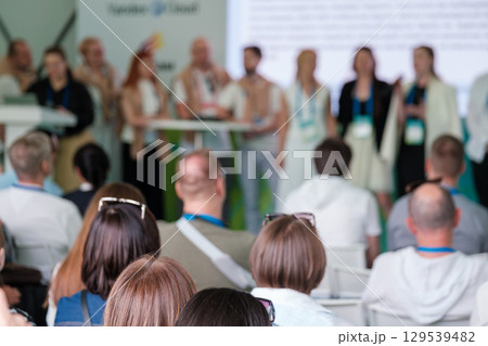 Audience watching a professional conference presentation with speakers on stage Audience watching a professional conference presentation with speakers on stage 129539482