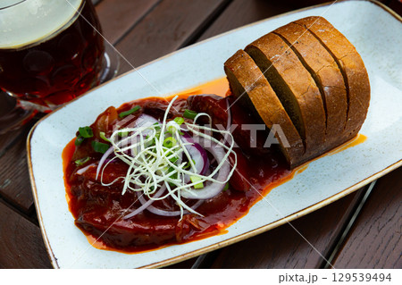 Baked sausages on beer, with red onion, peckles and toasted bread Baked sausages on beer, with red onion, peckles and toasted bread 129539494