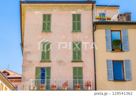 Windows with green wooden shutters. Flowers in pot on balcony. Italy summer day. Italian style facade 129541362