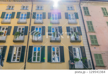 Windows with wooden shutters. Small balcony with flowers in summer. Italian style facade. Wall 129541364