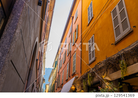 Narrow Italian street in Como city. Multicolor old house building architecture. Window shutter 129541369