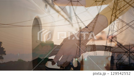 Image of electricity poles over hands of caucasian woman refueling car 129542552