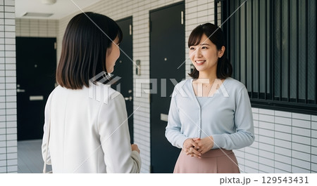 マンションの通路で立ち話をする2人の女性 129543431