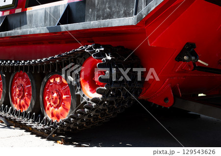 Close up photo of the red track of the all terrain vehicle. Metal track to improve the vehicle cross country ability. Alternative way of moving vehicles using track. Tank type all terrain vehicle 129543626