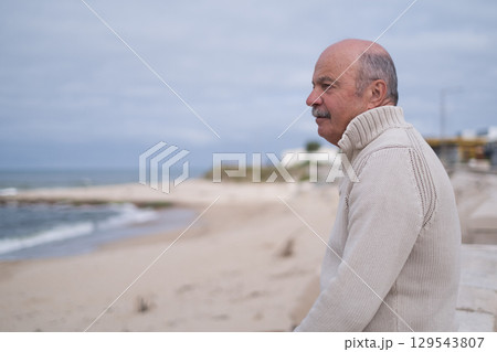 Elderly Portuguese Man Sitting on the Seafront and Looking at the Ocean 129543807