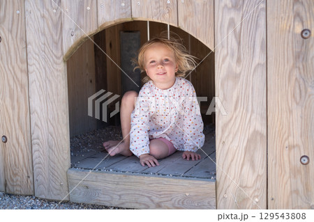 girl hiding from the heat in a playhouse on a playground in summer 129543808