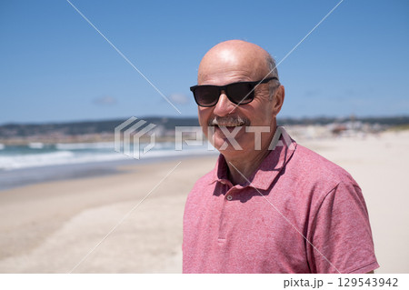 An elderly man with a mustache walking on the beach, enjoying his vacation. An elderly man with a mustache walking on the beach, enjoying his vacation. 129543942