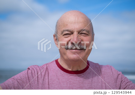 An elderly man with a mustache walking on the beach, enjoying his vacation. An elderly man with a mustache walking on the beach, enjoying his vacation. 129543944