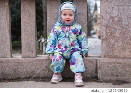 carefree toddler girl sitting after rain in summer day.  129543953