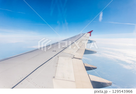 View from the airplane window at a beautiful cloudy sky and the airplane wing 129543966