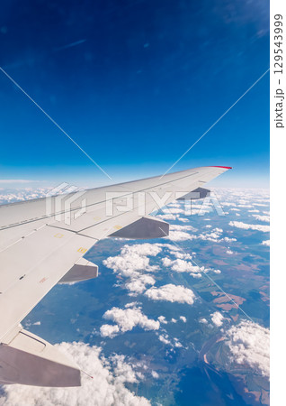 View from the airplane window at a beautiful cloudy sky and the airplane wing 129543999