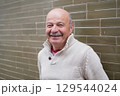 Elderly Spanish Man Standing by a Wall and Smiling 129544024