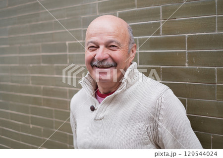 Elderly Spanish Man Standing by a Wall and Smiling 129544024