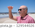 Elderly Man with Mustache and Sunglasses Looking into the Distance over the Ocean.  129544026