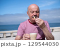 Elderly Man with Mustache Drinking Coffee at Outdoor Cafe on Vacation 129544030