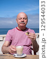 Elderly Man with Mustache Drinking Coffee at Outdoor Cafe on Vacation 129544033