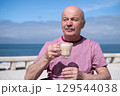 Elderly Man with Mustache Drinking Coffee at Outdoor Cafe on Vacation 129544038