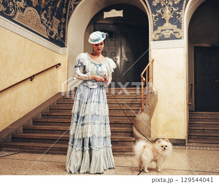 Elegant woman in blue dress with white fluffy Pomeranian dog outdoors Elegant woman in blue dress with white fluffy Pomeranian dog outdoors 129544041