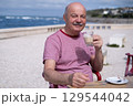 Elderly Man with Mustache Drinking Coffee at Outdoor Cafe on Vacation 129544042
