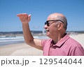 Elderly Man with Mustache and Sunglasses Looking into the Distance over the Ocean.  129544044