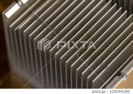 old grey aluminum radiator for cooling modern devices, part of an old used cooling system in the form of a metal alloy radiator, close up 129544160