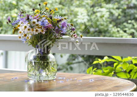 Bouquet of wild flowers in a glass vase on a wooden table Bouquet of wild flowers in a glass vase on a wooden table 129544630