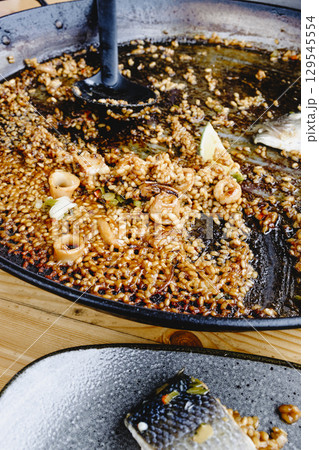 plate with fish and rice from the paella pan 129545554