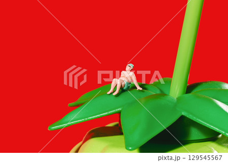 a miniature man rests on a green leaf a miniature man rests on a green leaf 129545567