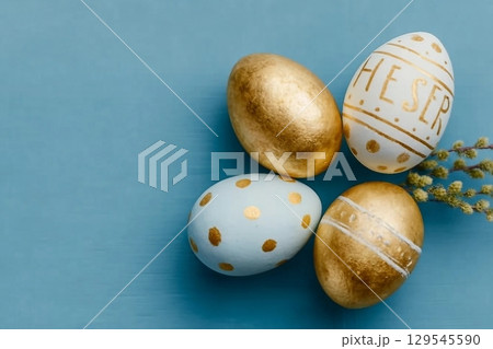 Easter background. Easter golden decorated eggs on blue background. Minimal easter concept. Flat Lay of Golden Easter Eggs 129545590