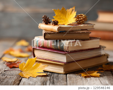 Stack of vintage books with autumn leaves and a pencil 129546146