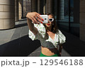 Woman make selfie with smartphone in paris, france. Woman with mobile phone on colorful background. Girl in sunglasses with fashion look and sensual beauty. New technology and modern life. 129546188