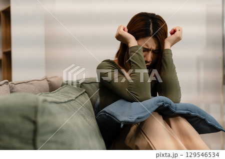 Woman sitting in sofa holding pills, having stress, boredom, loneliness, anxiety. 129546534
